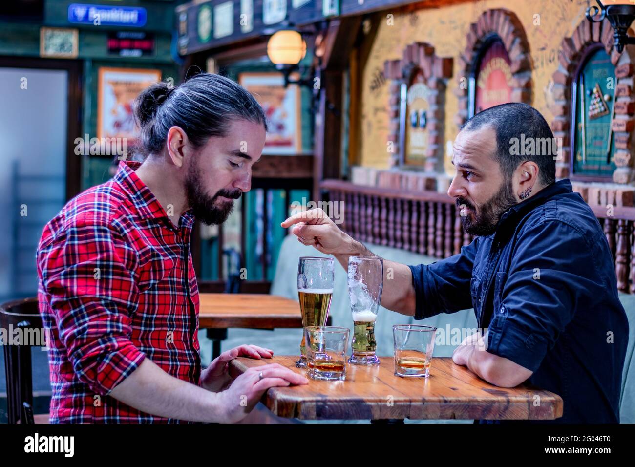 Two male friends drinking whiskey and beer together at the pub. They are drunk and they are