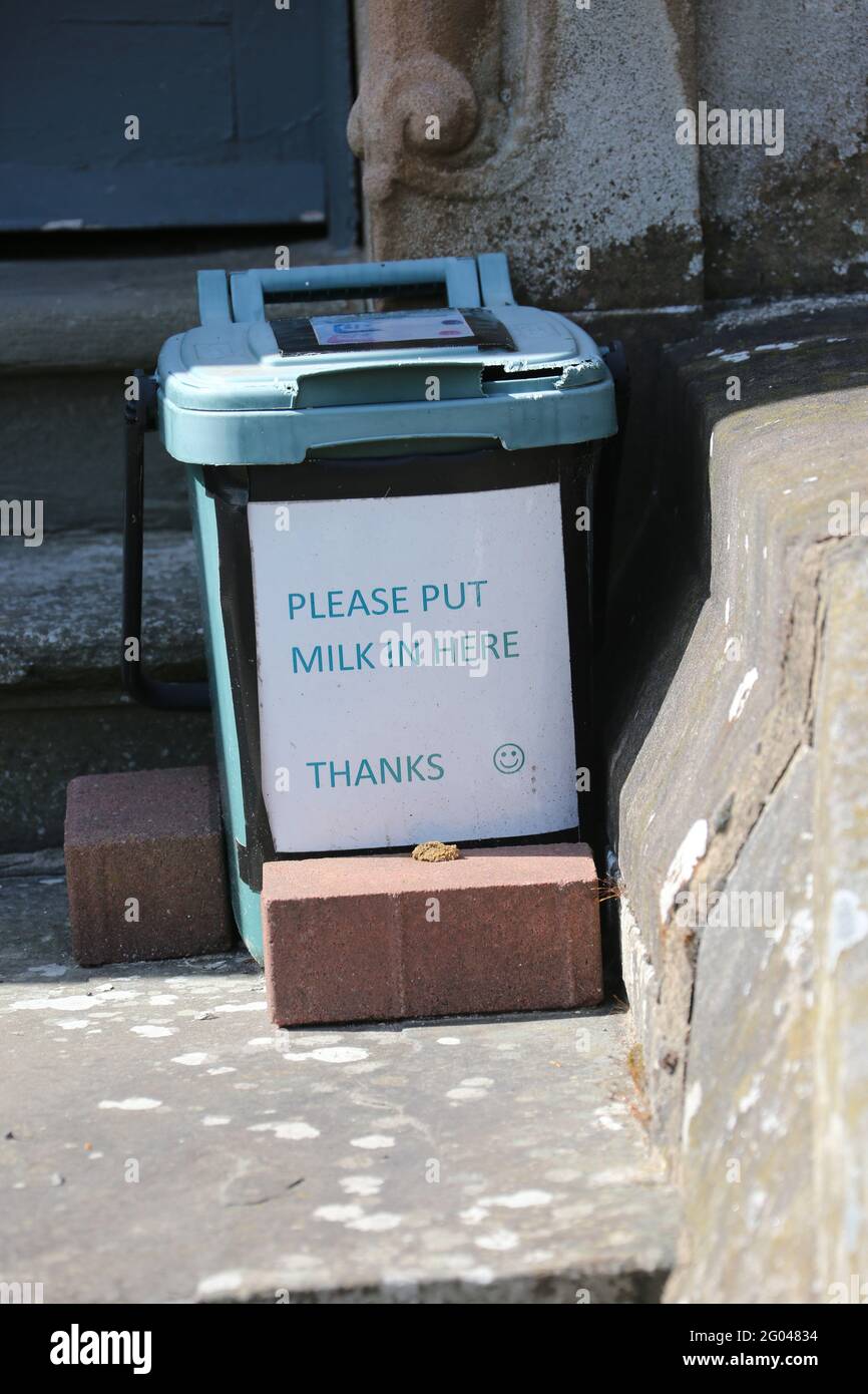 Creative idea for use of a recyling food bin, container. Food bin being used a box to put milk in on doorstep Stock Photo