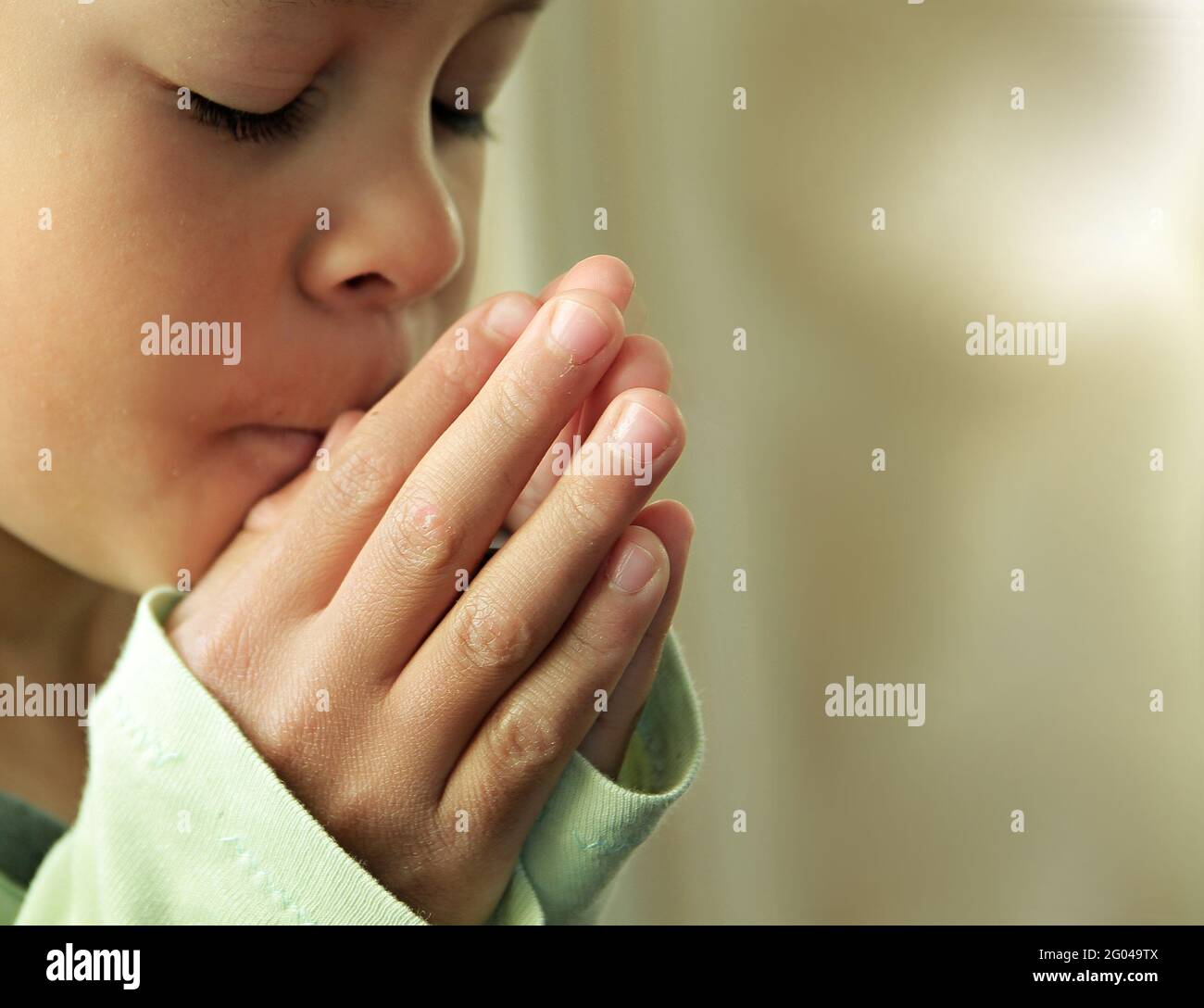 boy praying to god with closed eyes and hands held together stock photo Stock Photo
