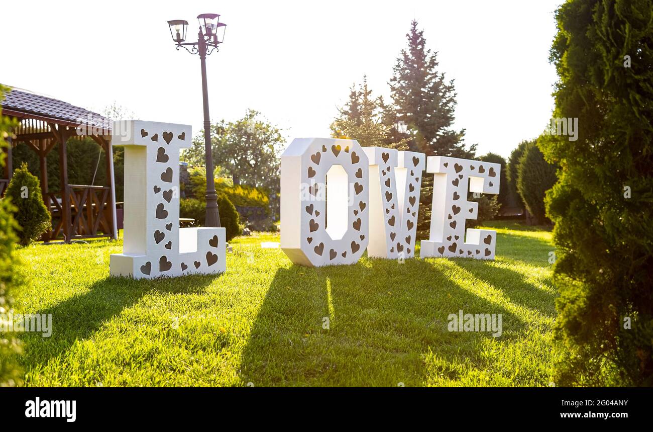 Photozone. Wedding decor. Large white letters with the inscription love on the green grass. Valentine's Day. Sense. Decor in the middle of green grass Stock Photo