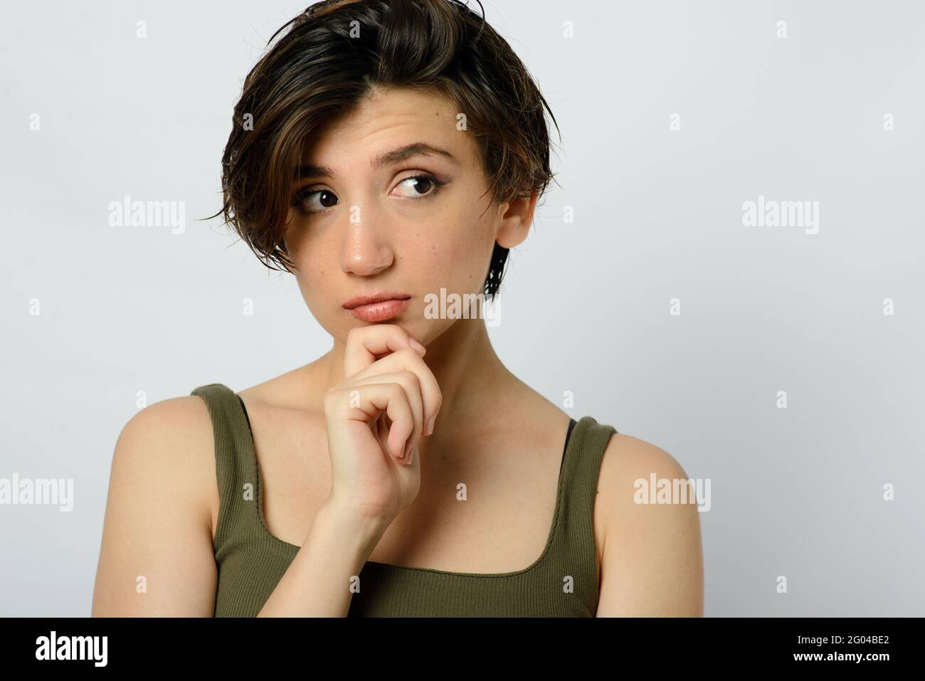 Portrait of a young woman with short and wet hair and a thoughtful emotion on her face on a white background. Stock Photo