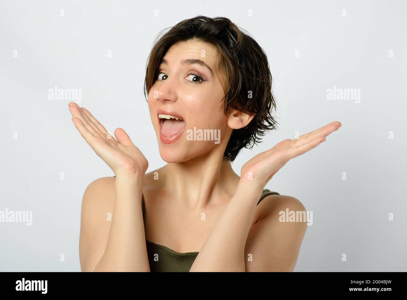 Portrait of a young woman with short and wet hair and a funny emotion on her face on a white background. Stock Photo