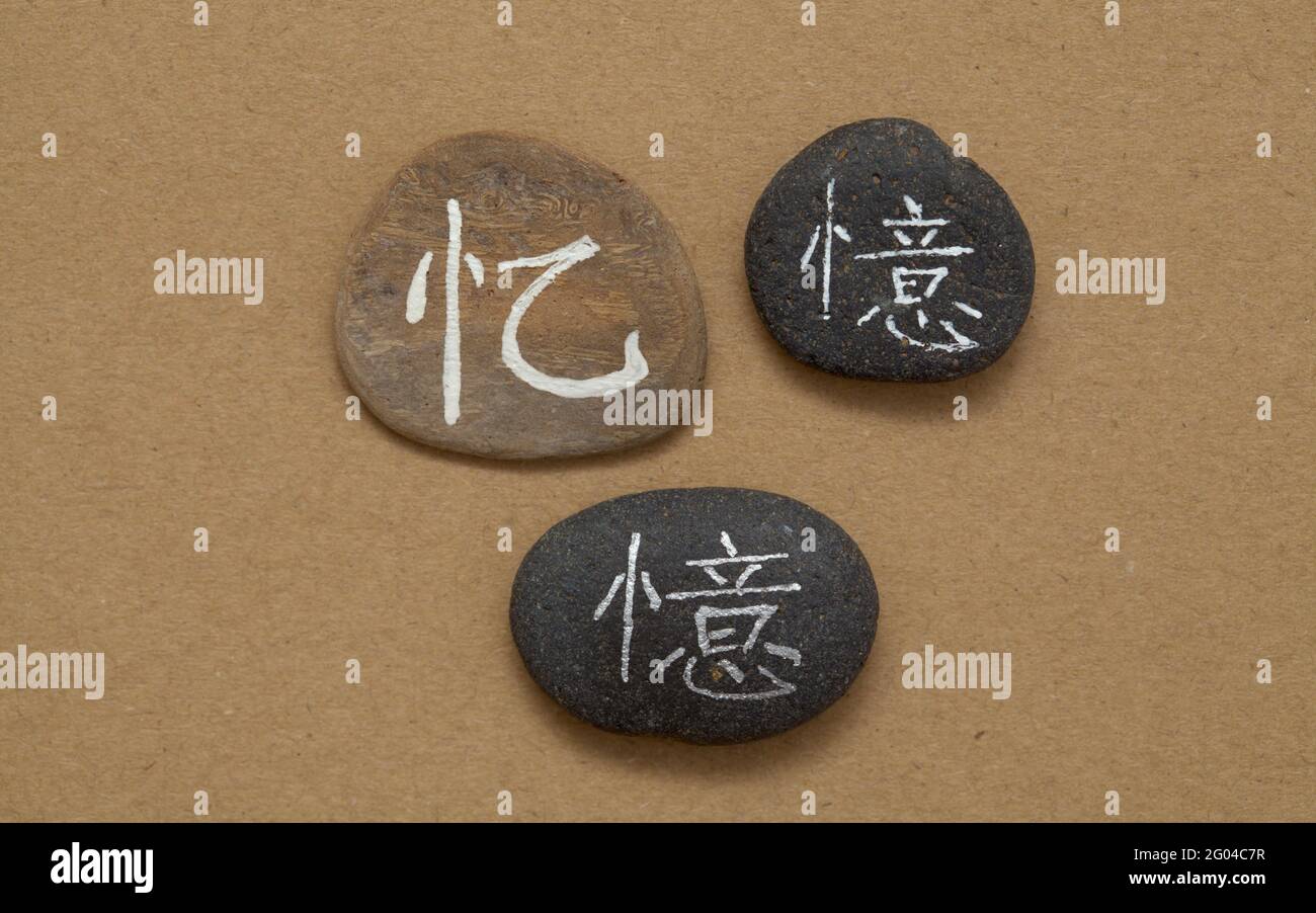 Chinese character yi or Japanese oku, meaning memory, written on a volcanic rock pebble Stock Photo