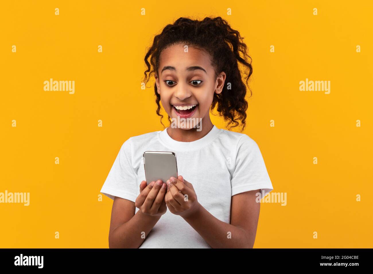 Excited black girl using mobile phone at studio Stock Photo