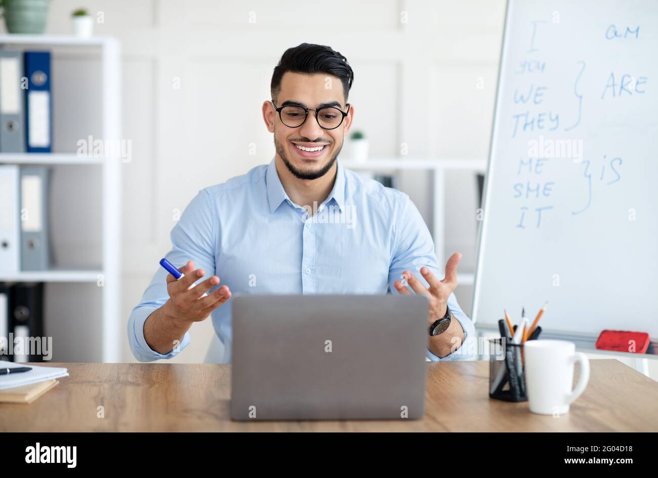 Online languages school. Arab male English teacher giving remote lesson on laptop computer at home office Stock Photo