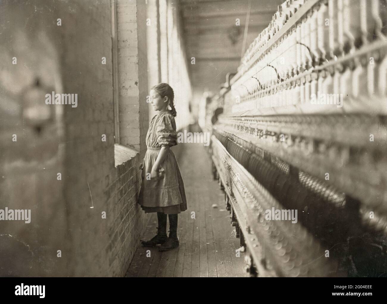 Child Labour: A ten year old spinner looking out of the window of her factory Stock Photo