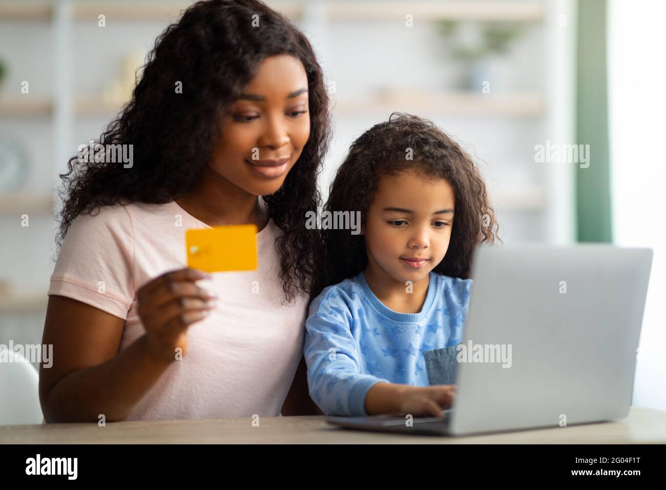 African American mother shopping online with credit card, making