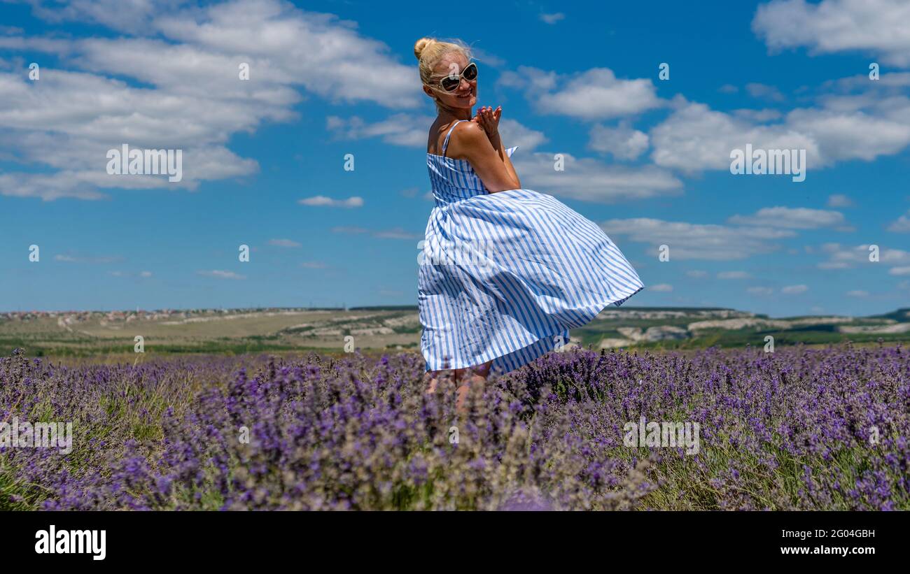 Happy lady in lilac field adult with charismatic appearance glasses chamelleons standing beautiful with perfect smile stands field purple young, woman Stock Photo