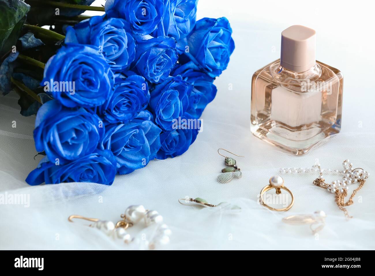 Beautiful blue roses, perfume and jewelry on light background Stock Photo -  Alamy