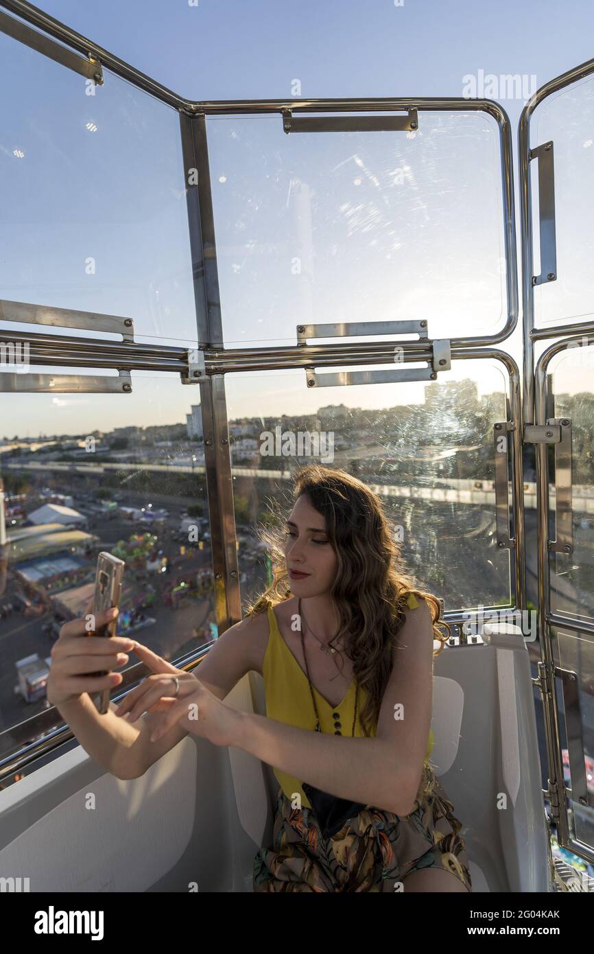 Vertical shot of a Caucasian female taking a selfie in a Ferris wheel Stock Photo