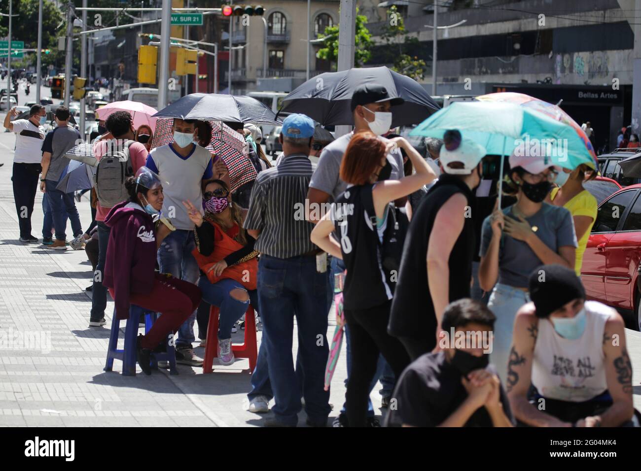 Caracas, Venezuela. 31st May, 2021. People with umbrellas stand and sit while waiting to get a vaccination against Corona. Officials say 232,800 people nationwide have been infected with Covid-19. The Ministry of Health informs a mortality rate of 1.12 percent. Credit: Jesus Vargas/dpa/Alamy Live News Stock Photo