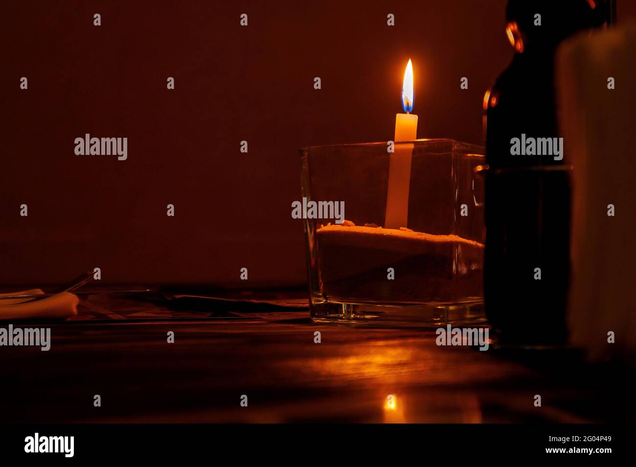 Burning candle on a table in a restaurant in a glass candlestick. Stock Photo