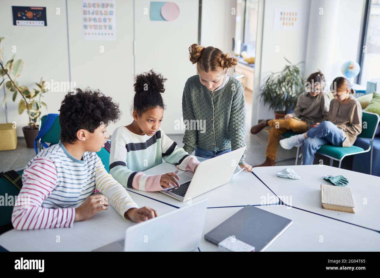 High angle view at diverse group of children working together at desk in classroom at modern school, copy space Stock Photo