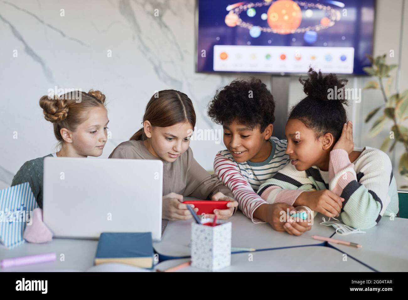 Diverse group of children studying together at table in modern school, copy space Stock Photo