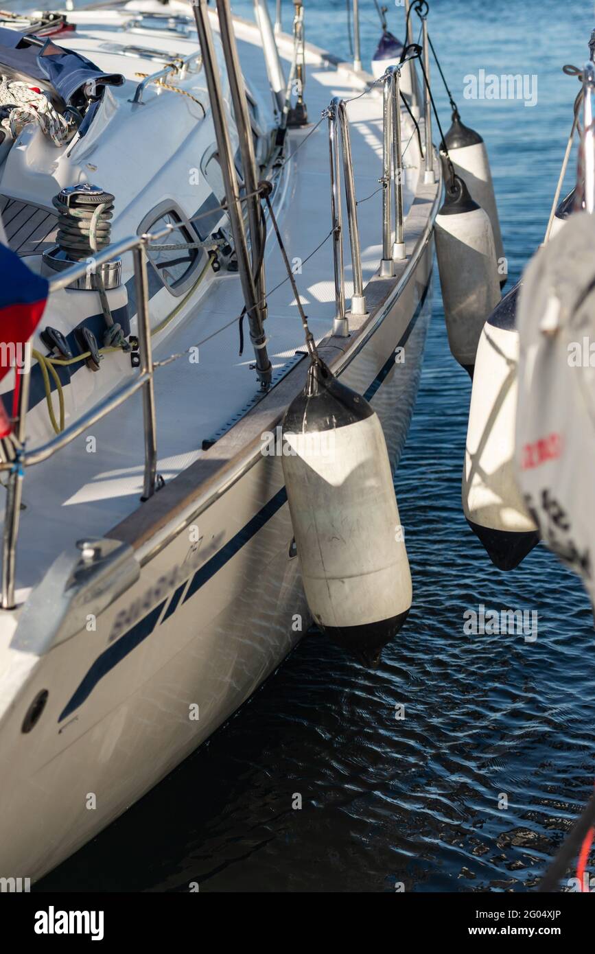 The side of a yacht with mooring fenders next to another yacht. Tight mooring of yachts in the marina. They stand tightly sideways. Stock Photo