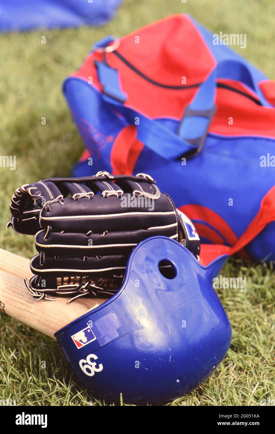 Misc. baseball equipment sitting on the field, bat, glove, helmet, bag