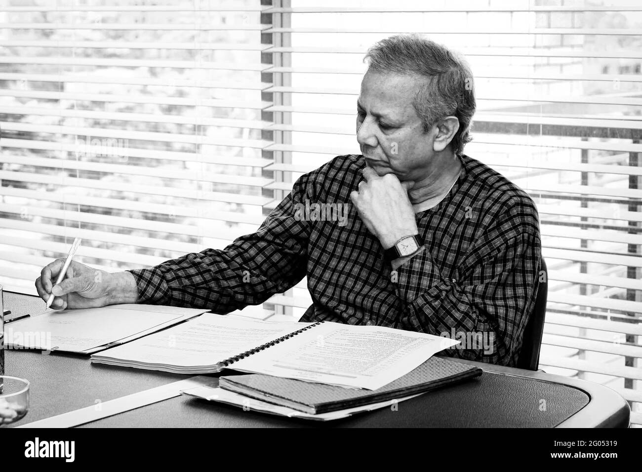 Bangladesh – September 20, 2012: Muhammad Yunus a popular economist and leader is writing on the table at a conference at Grameen centre, Dhaka. Stock Photo