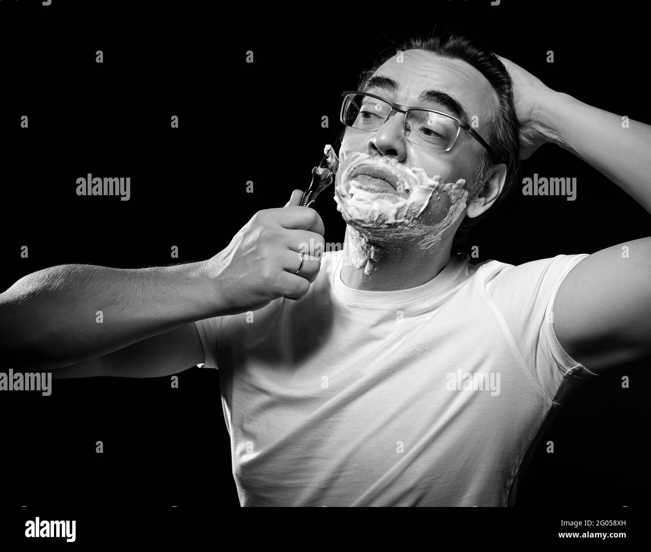 https://c8.alamy.com/comp/2G058XH/black-and-white-portrait-of-man-in-white-t-shirt-and-glasses-shaving-with-razor-blades-and-gel-foam-and-looking-aside-2G058XH.jpg