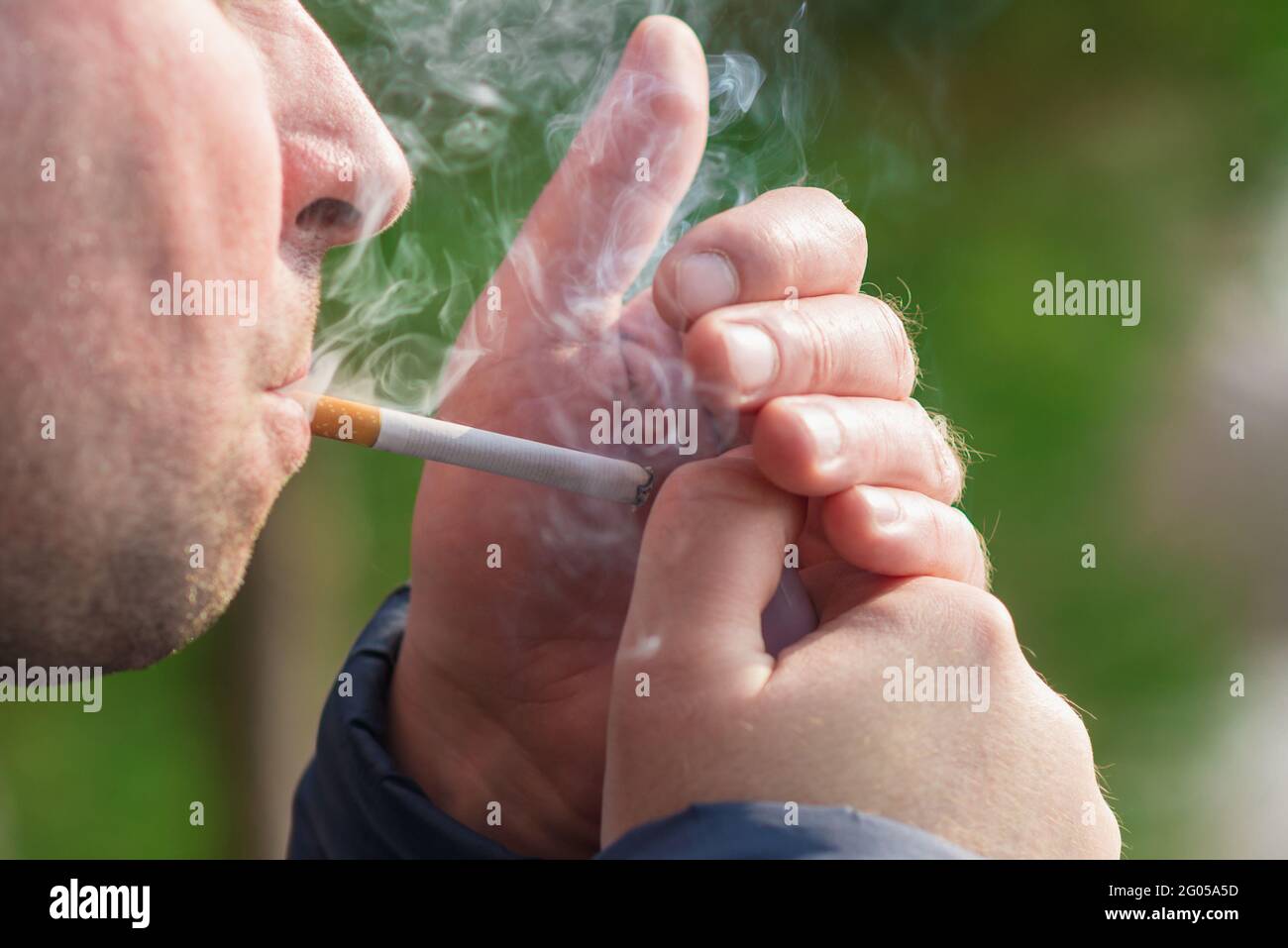 Cropped close up man light a cigarette outdoors shot Stock Photo