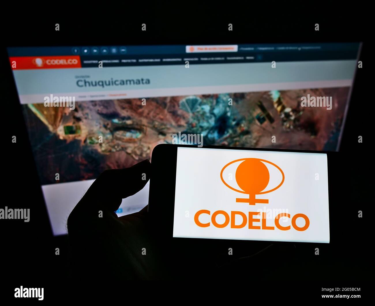 Person holding smartphone with logo of Chilean mining company Codelco on screen in front of website. Focus on phone display. Stock Photo