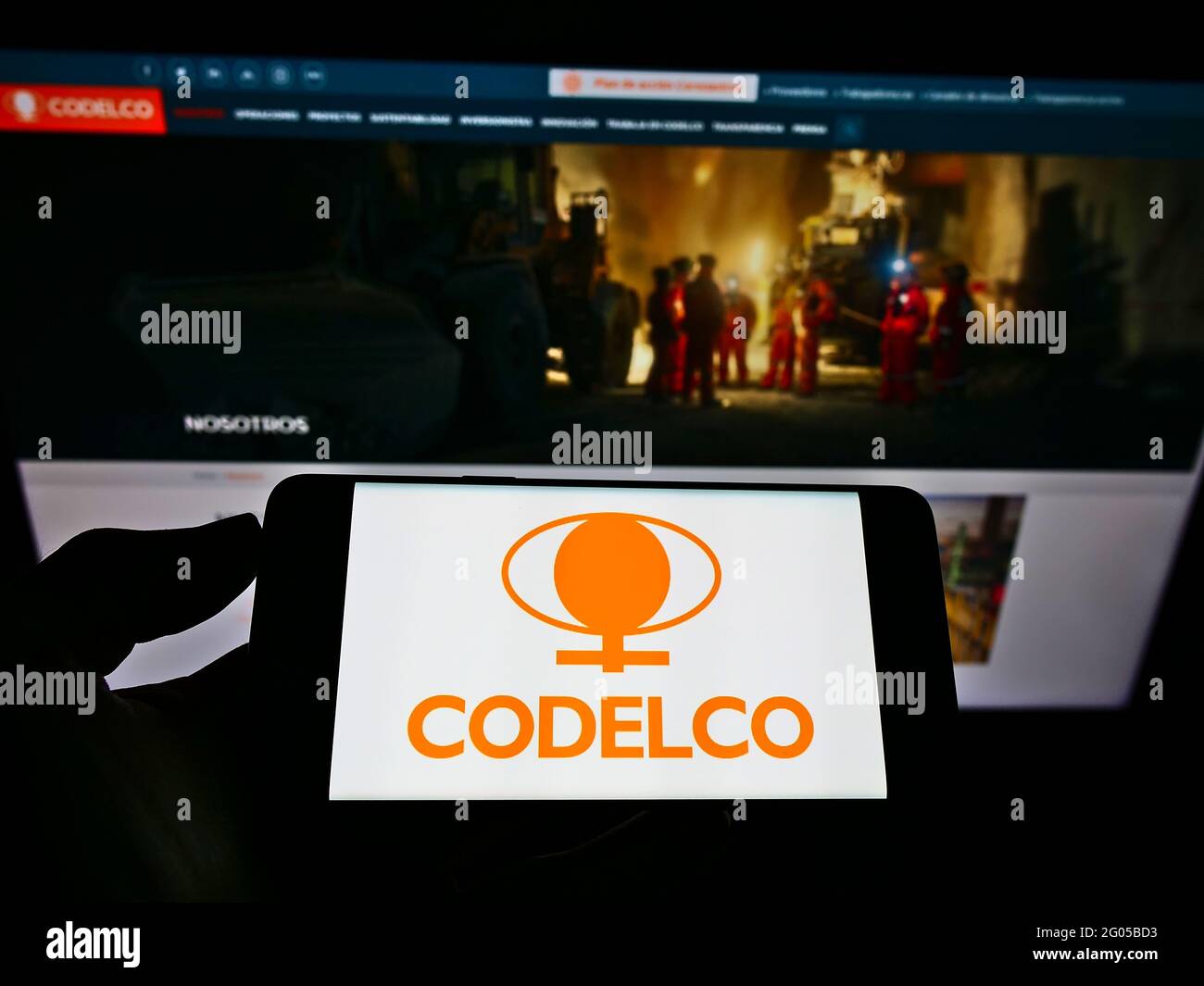 Person holding mobile phone with business logo of Chilean mining company Codelco on screen in front of web page. Focus on phone display. Stock Photo