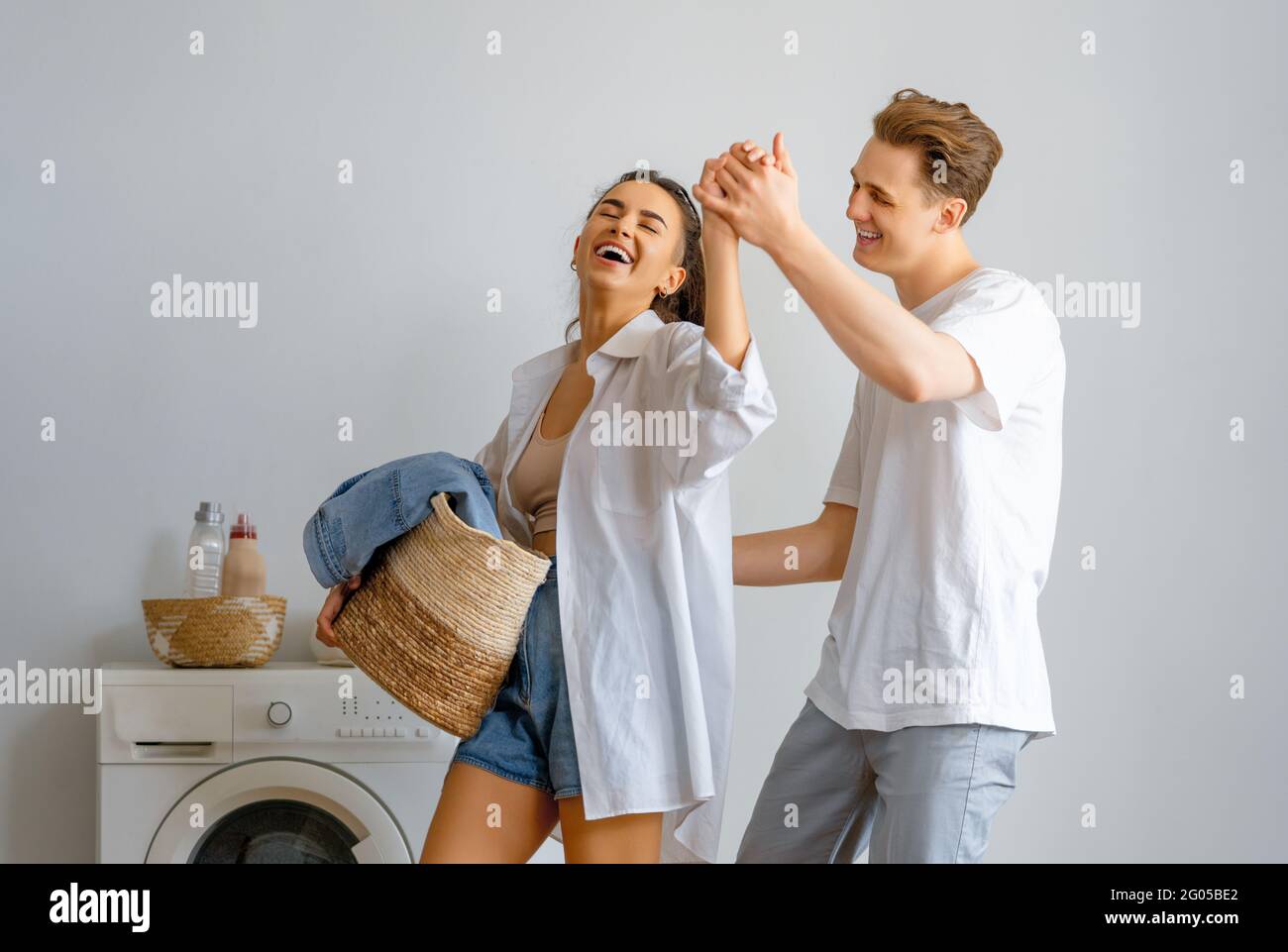 Beautiful young loving couple is smiling while doing laundry at home ...