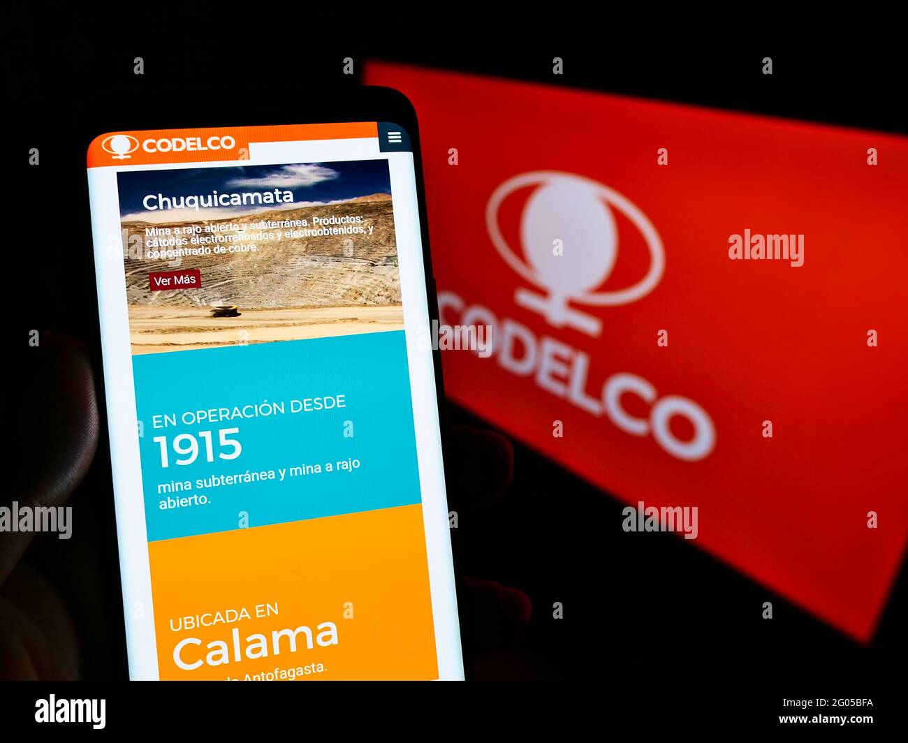 Person holding mobile phone with website of Chilean mining company Codelco on screen in front of business logo. Focus on center of phone display. Stock Photo