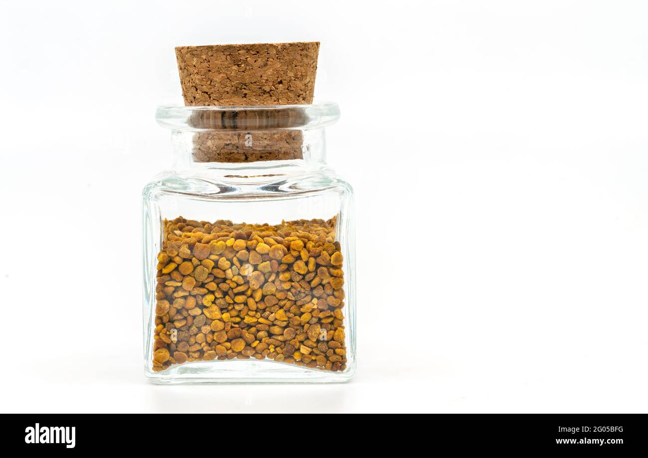 Close up bee pollen or flower pollen in a cleared glass container, rectangular and short shape with a cork stopper. The image on white background, fro Stock Photo
