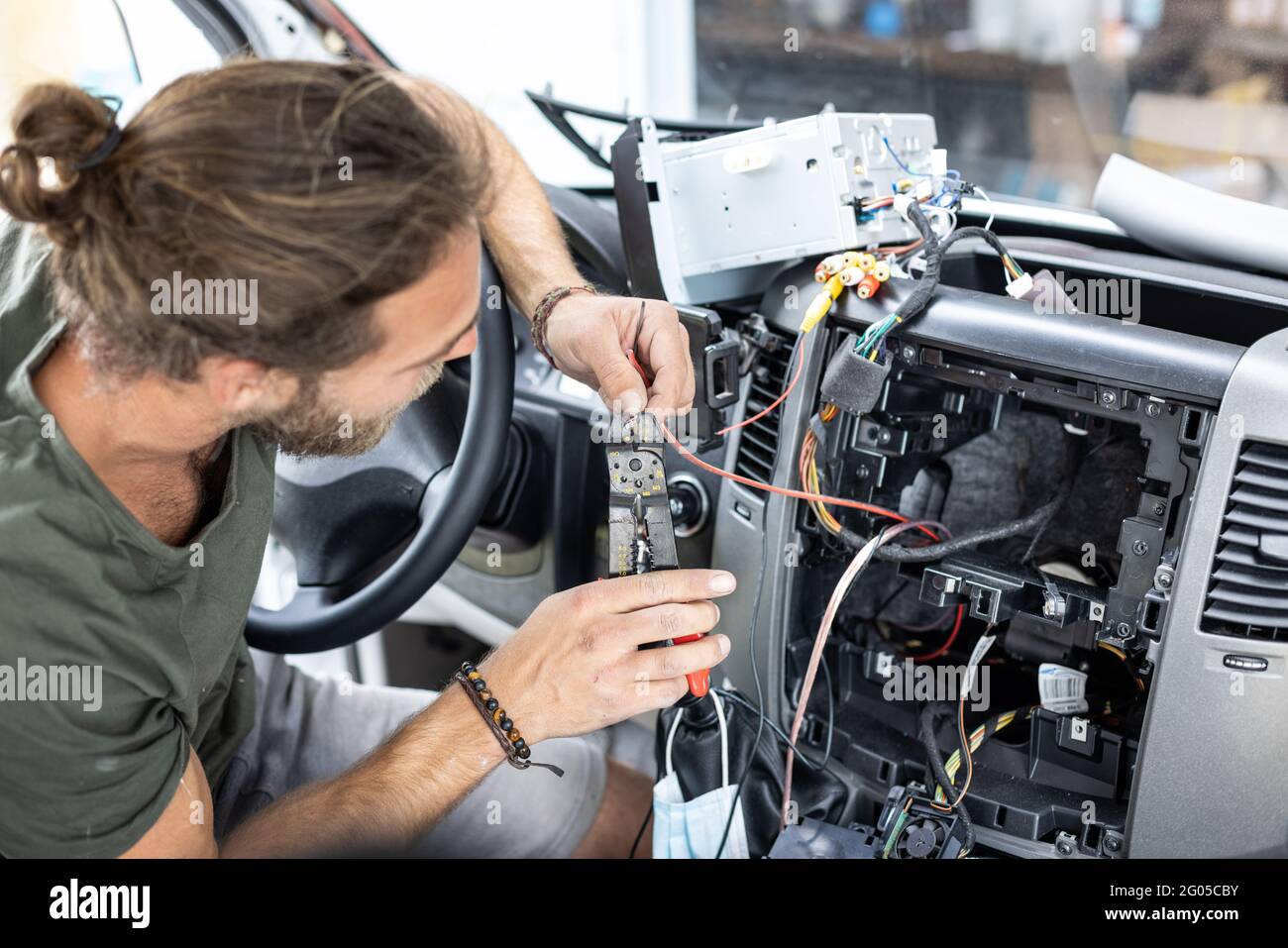 Man working on electronics inside the center console of a car Stock Photo