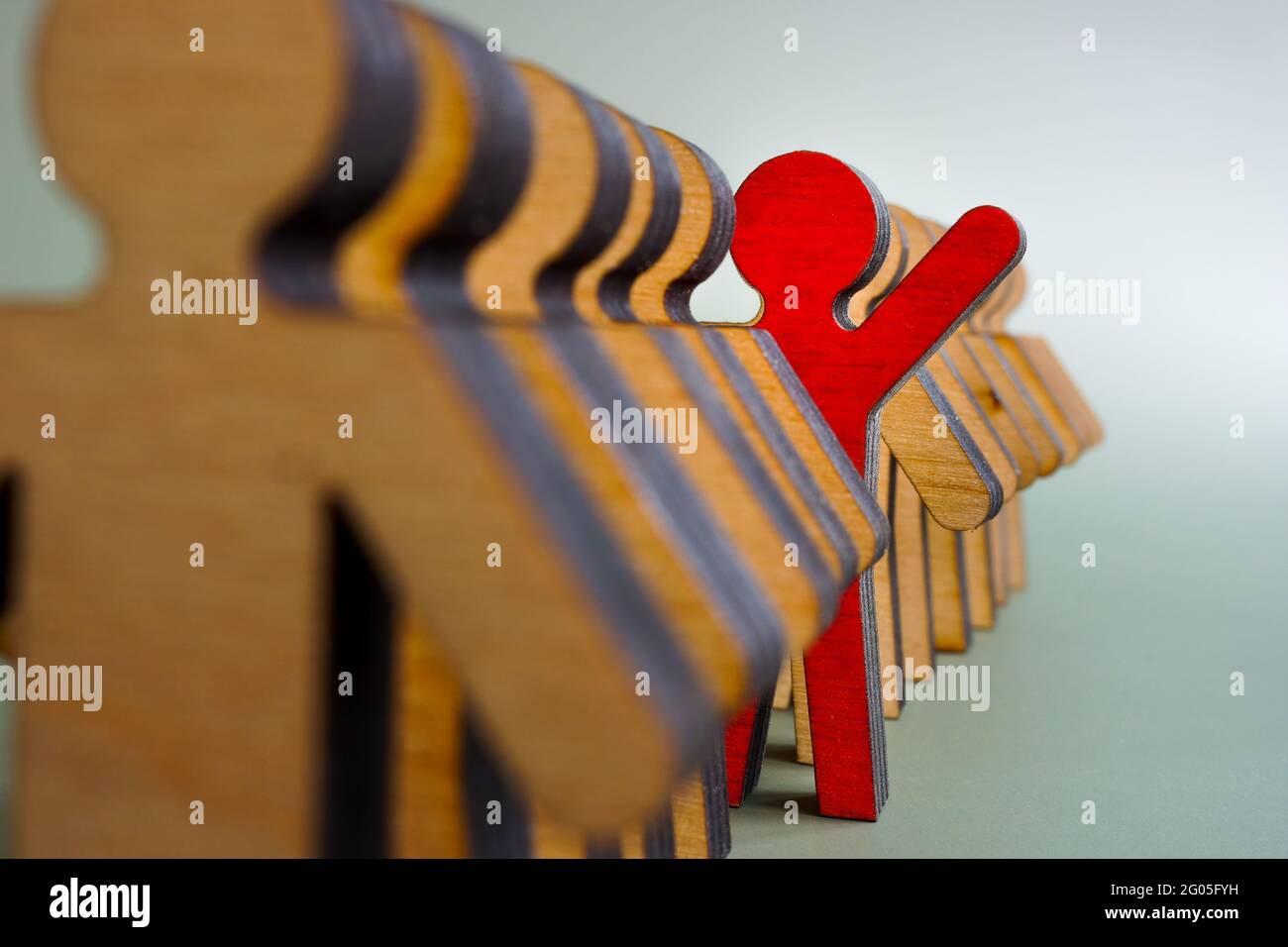 Activist stand out from the crowd concept. The red figurine is in the line of others. Stock Photo