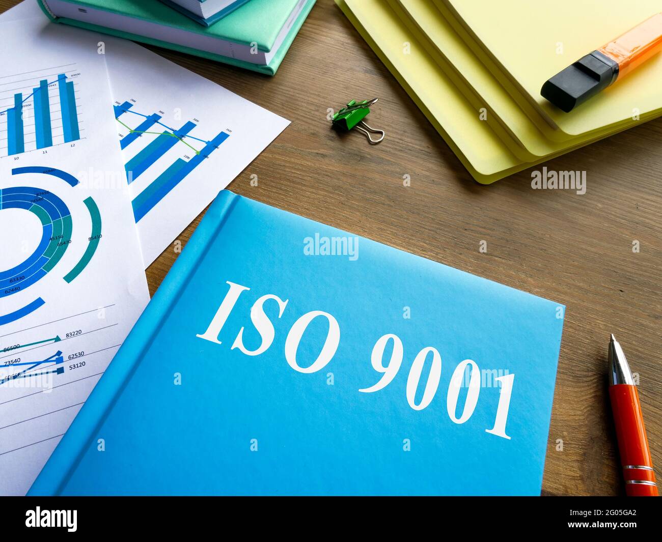 Book about iso 9001 and heap of papers. Stock Photo