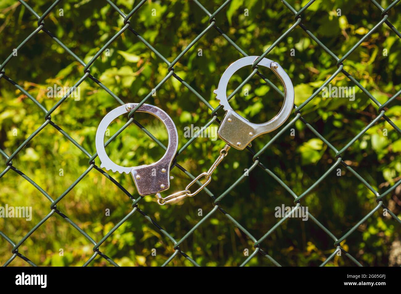 Handcuffs hanging on the metal fence with nature background Stock Photo