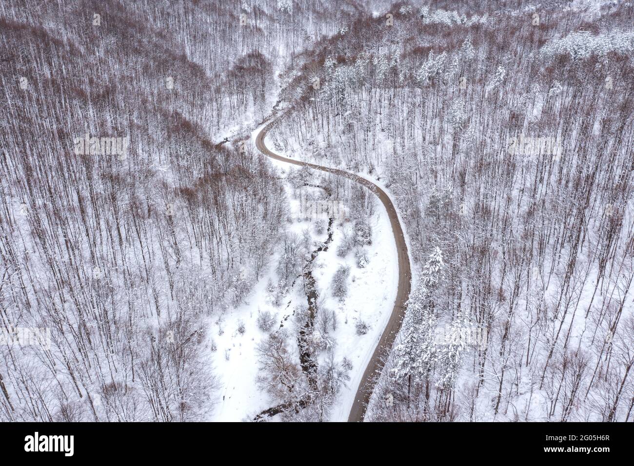 Aerial winter landscape with winding curvy road and meandering mountain stream Stock Photo