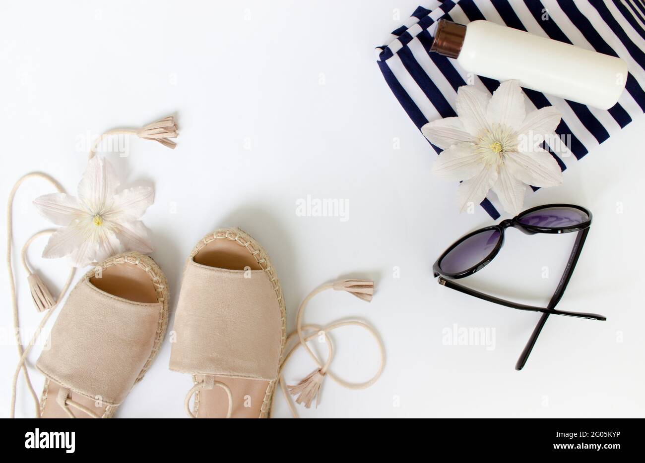 Summer Flat lay. Summer sandals, white flowers, sunglasses and a white bottle.Top view. Creative background. Stock Photo