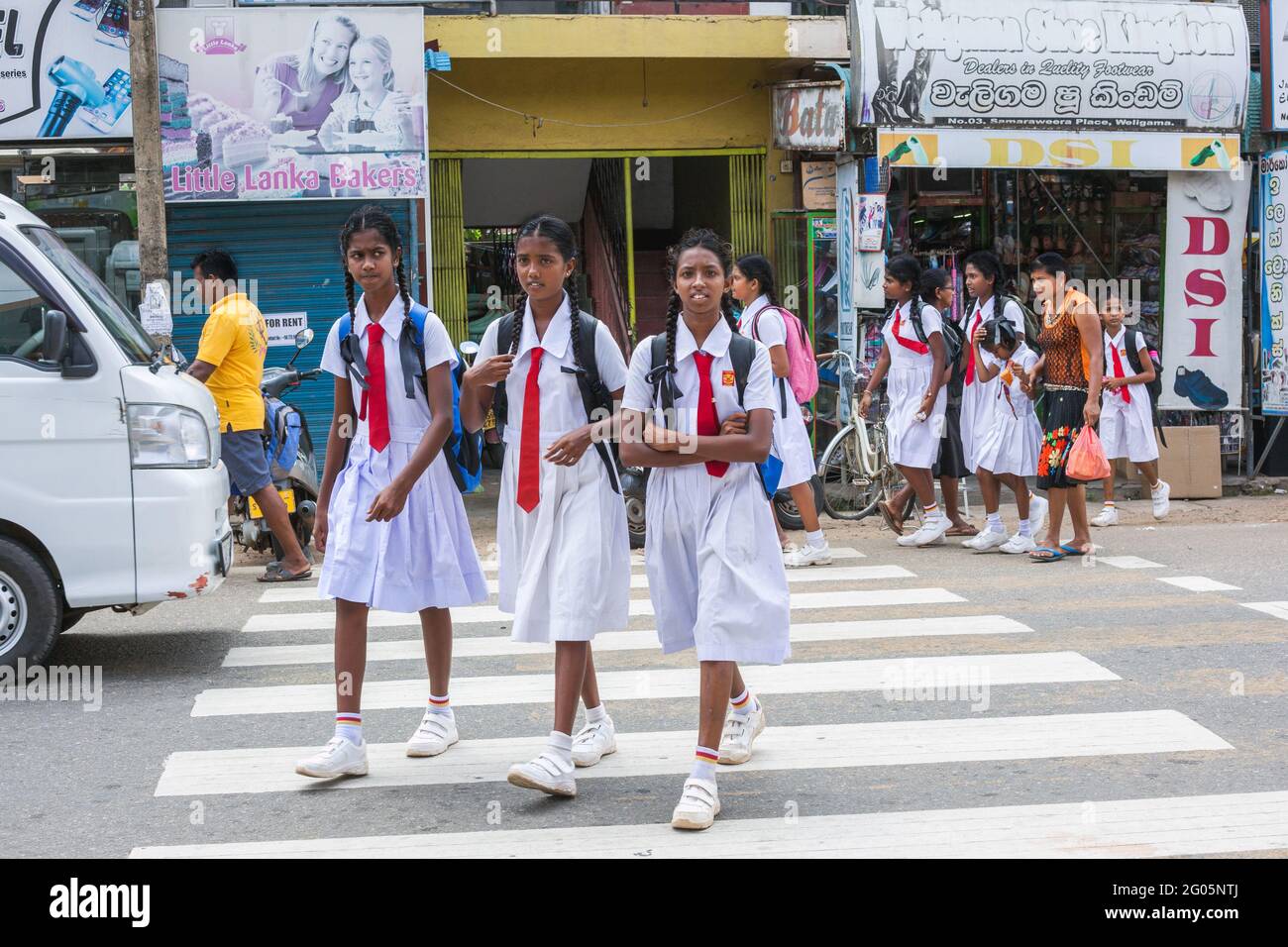 Sri lankan schoolgirls in white school uniform cross zebra crossing after school, Weligama, Southern province, Sri lanka Stock Photo