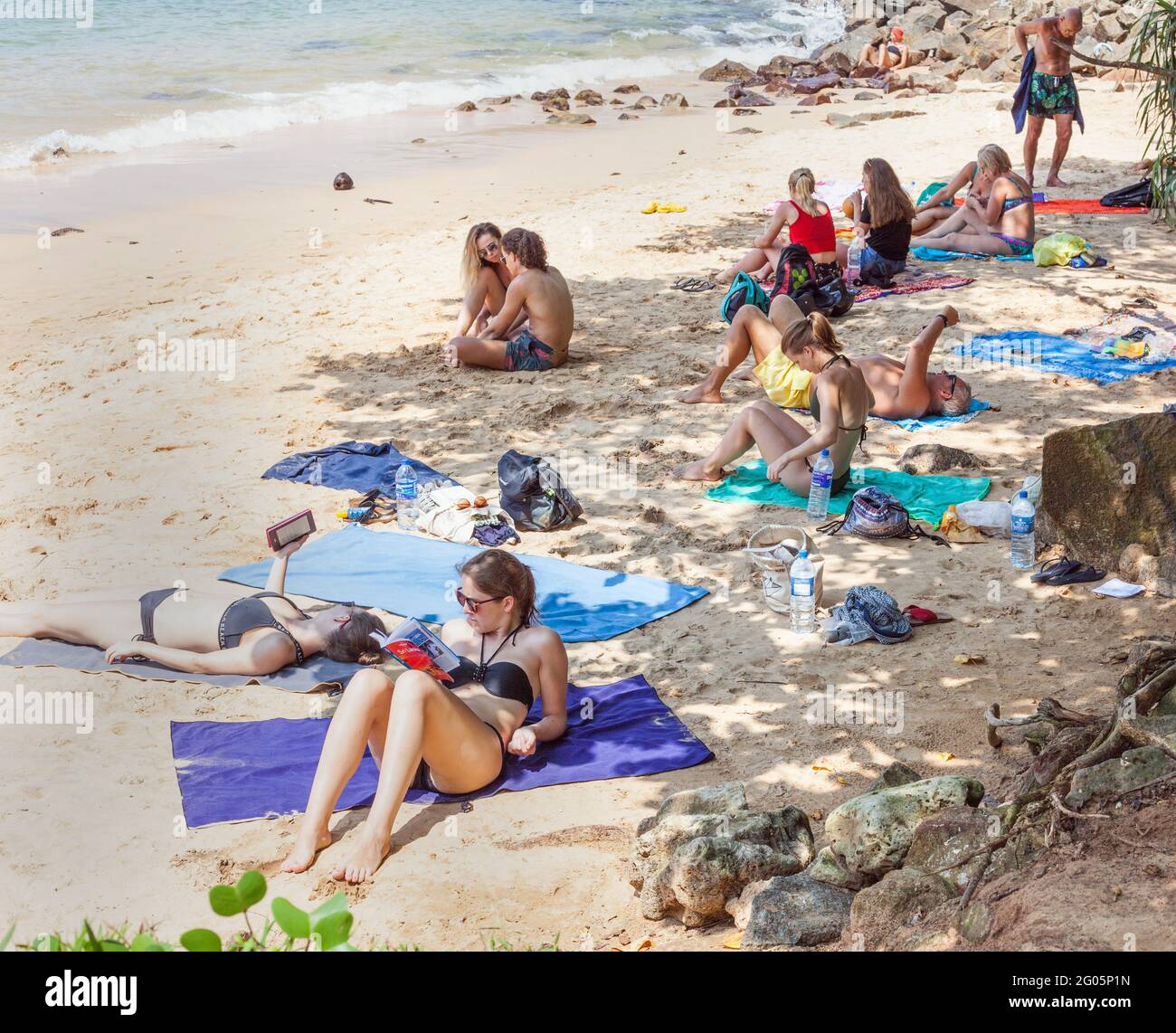 Western tourists wearing bikinis sunbathing and relaxing on white sand beach, Jungle Beach, Unawatuna, Southern province, Sri Lanka Stock Photo