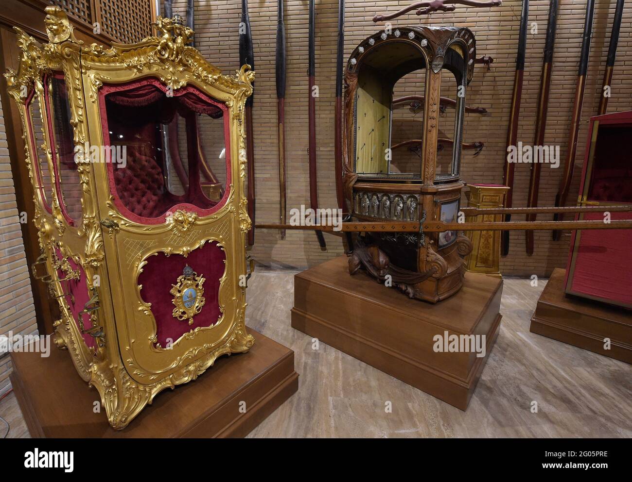 Sedan chairs of Pope Leo XIII within the carriage pavillon of the Vatican Museums on March 2021.- Inaugurated in 1973 by pope Paul VI the carriage pavillon (Padiglione delle Carrozze) of the Vatican Museums shows a collection of ceremonial berlins, sedan chairs, various automobiles and popemobiles belonging to Pontiffs or Princes of the Holy Roman Church. - LEFT: Donated by by the Chamberlains of Sword and Cape to Leo XIII for the fiftieth anniversary of his ordination as bishop (1893). This splendid sedan chair, engraved and gilded throughout, is decorated with elegant motifs of plants, flowe Stock Photo