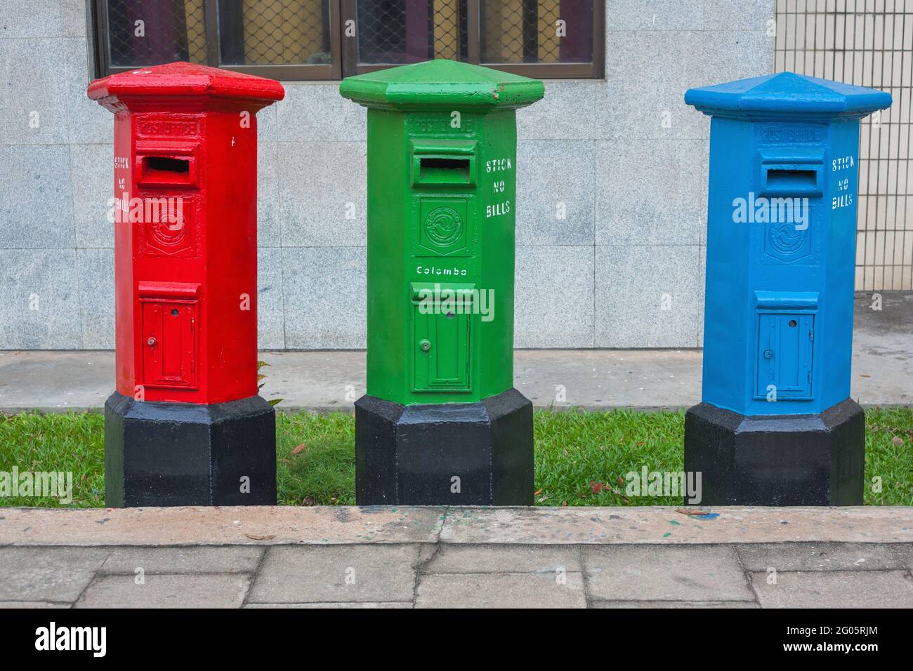 Three Royal Mail collection post boxes coloured red, green and blue on sidewalk in Colombo, Sri Lanka Stock Photo