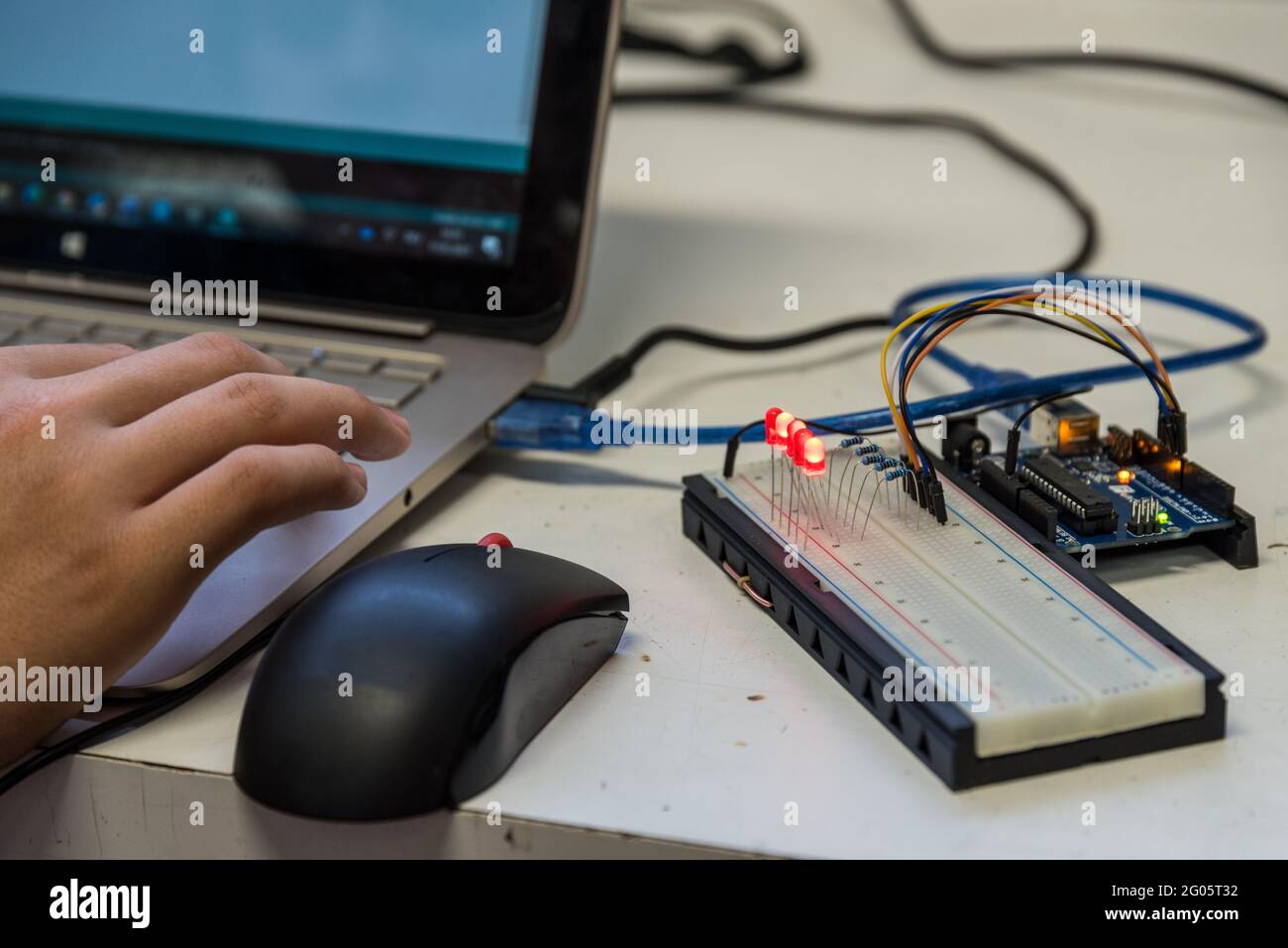 Skilled Worker Works On A Laptop With Electrical Engineering Components Stock Photo