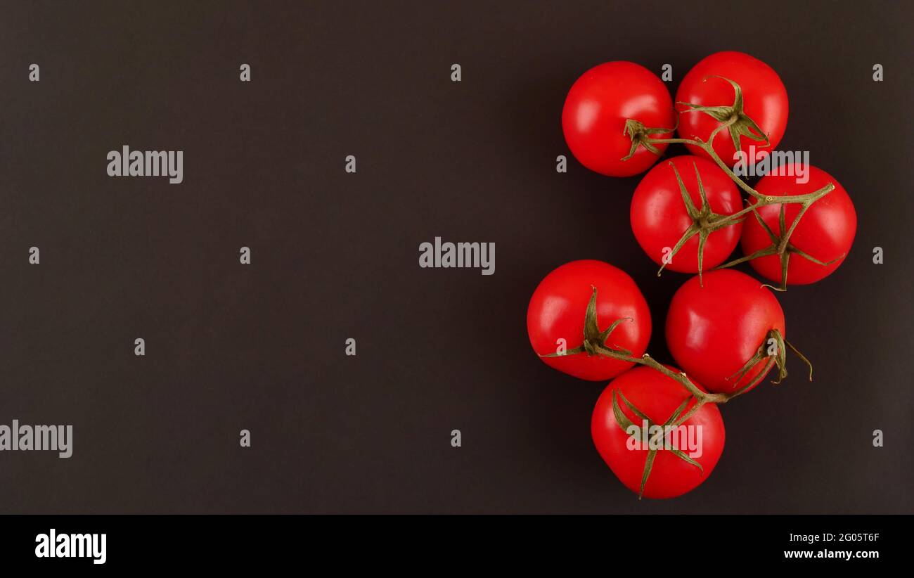 Fresh cherry tomatoes on a black background with spices. Top view with ...