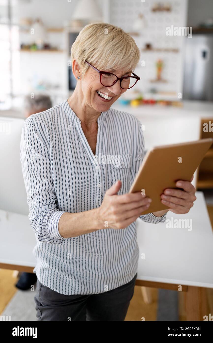 Beautiful happy senior woman using tablet computer at home Stock Photo