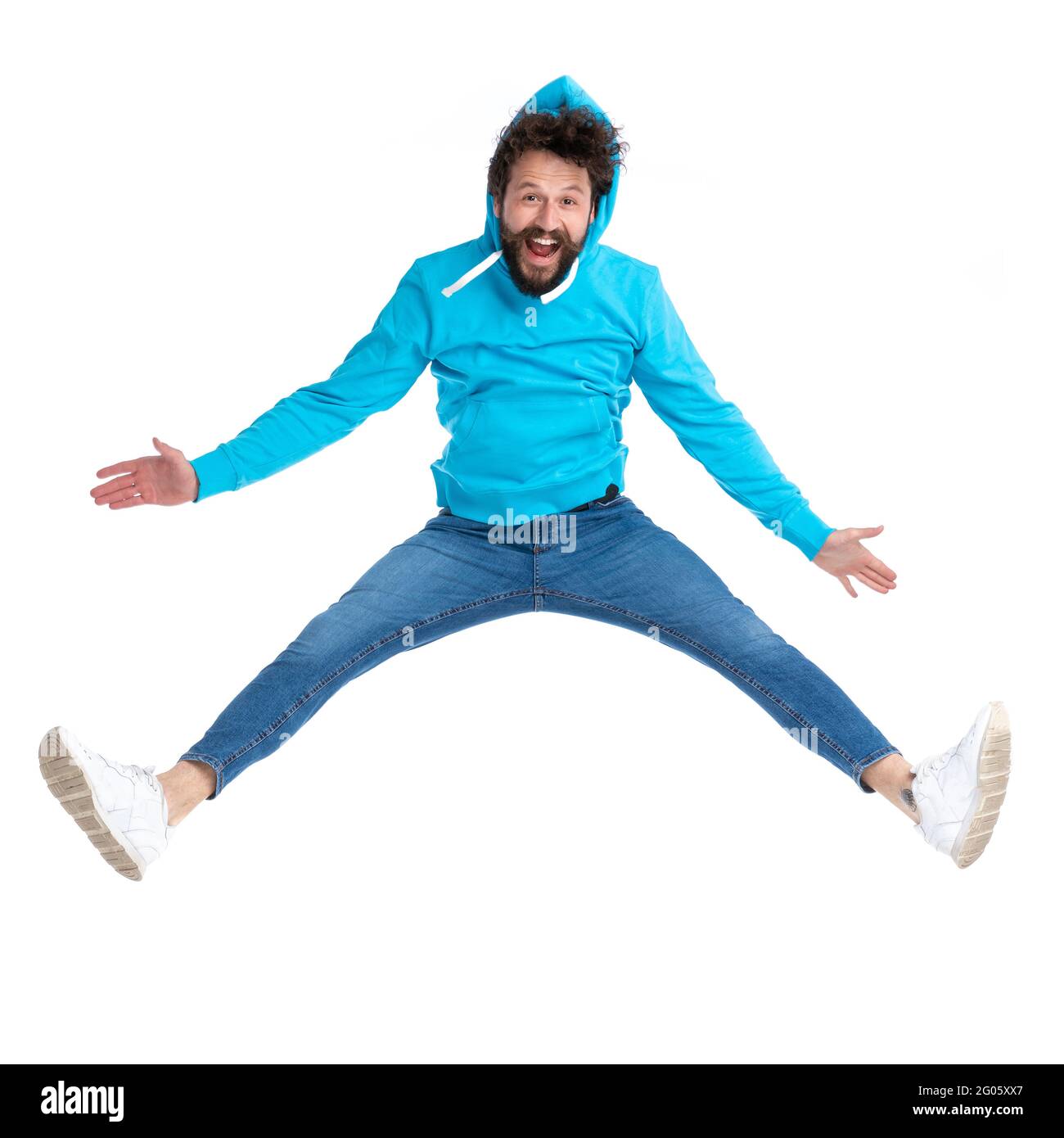 happy young guy in blue hoodie dynamically jumping, having fun and smiling while posing isolated on white background in studio Stock Photo