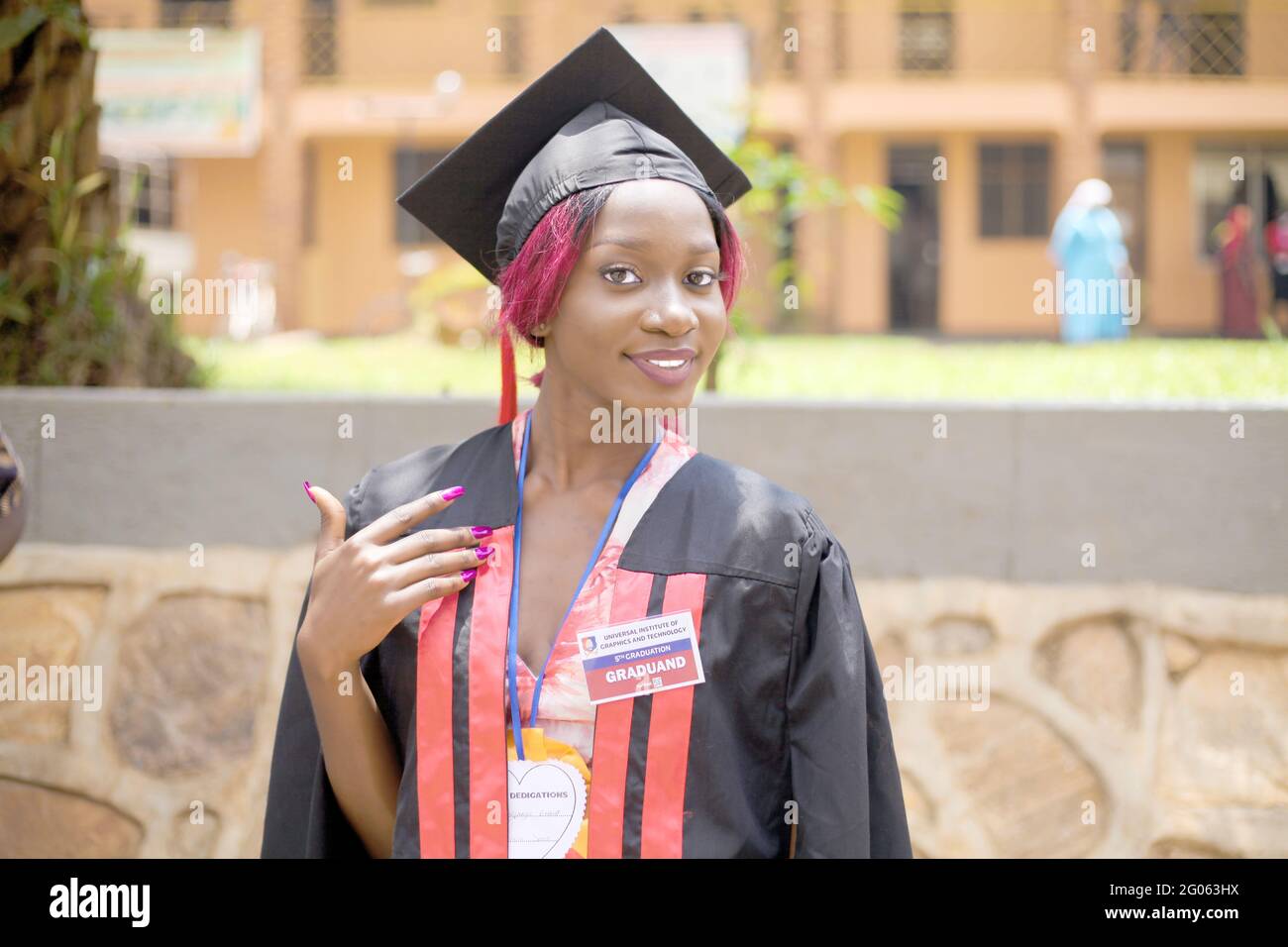 KAMPALA, UGANDA - May 31, 2021: Graduate graduates with with a huge smile looking happy and is a beautiful African American lady with the blurred back Stock Photo