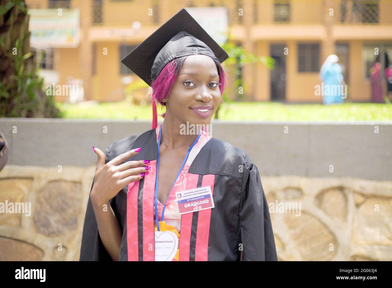 KAMPALA, UGANDA - May 31, 2021: Graduate graduates with with a huge smile looking happy and is a beautiful African American lady with the blurred back Stock Photo