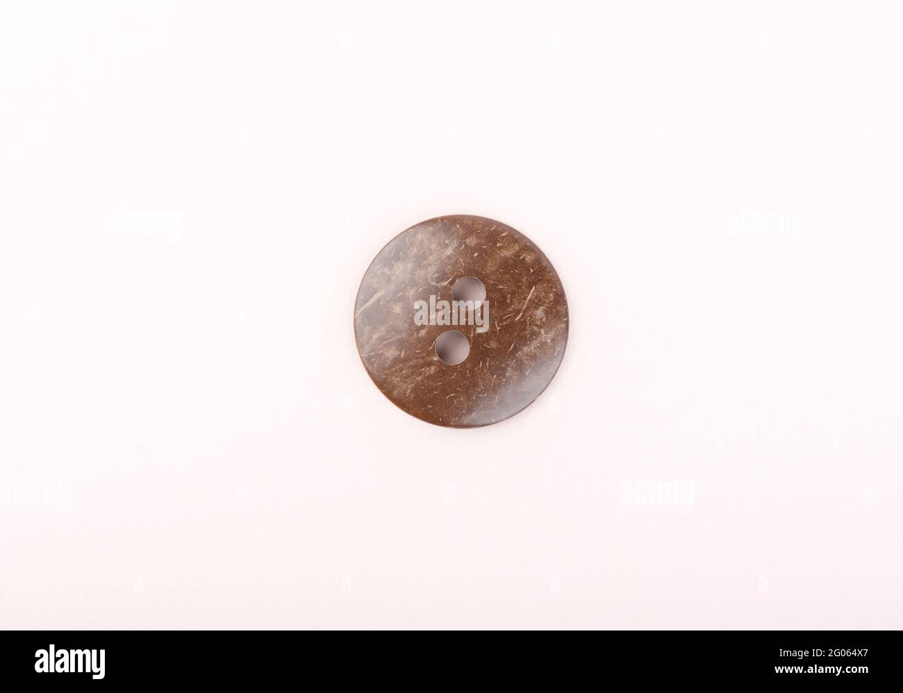 The brown plastic sewing button is marbled. Top view. Copy space. Stock Photo