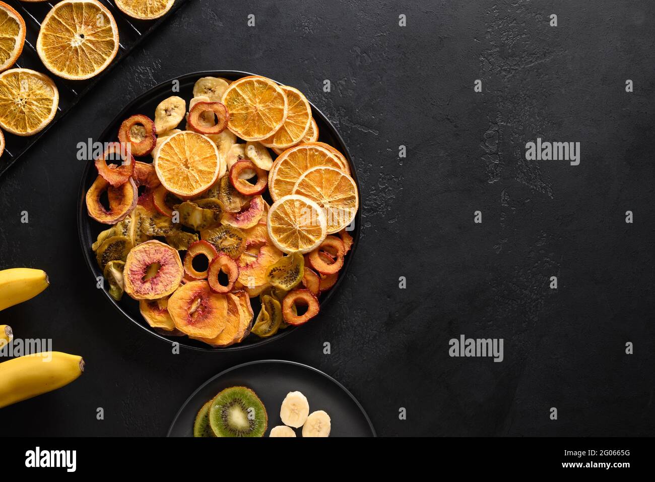 Dried different fruits sliced plums, kiwi, peach chipson black