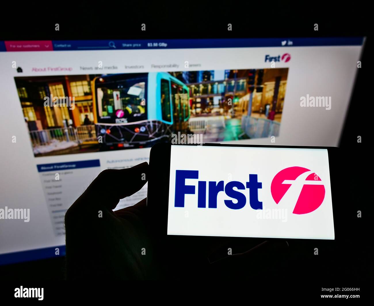 Person holding cellphone with logo of British transport company FirstGroup plc on screen in front of business website. Focus on phone display. Stock Photo