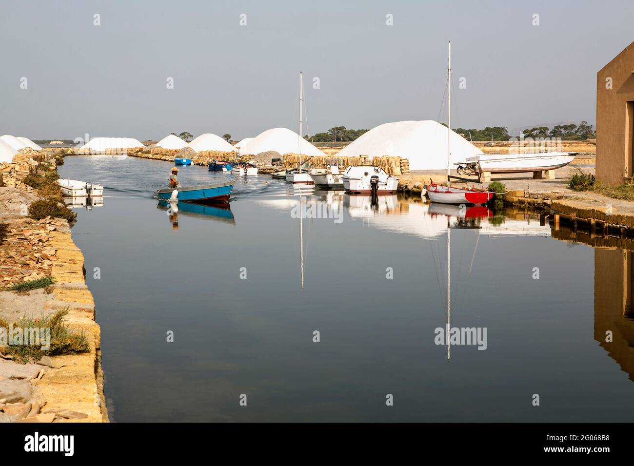 Saltworks, canal, man in boat, Saline of Trapani, salt, windmill, nature reserve, Stagnone of Marsala, Sicily, Italy, Europe Stock Photo