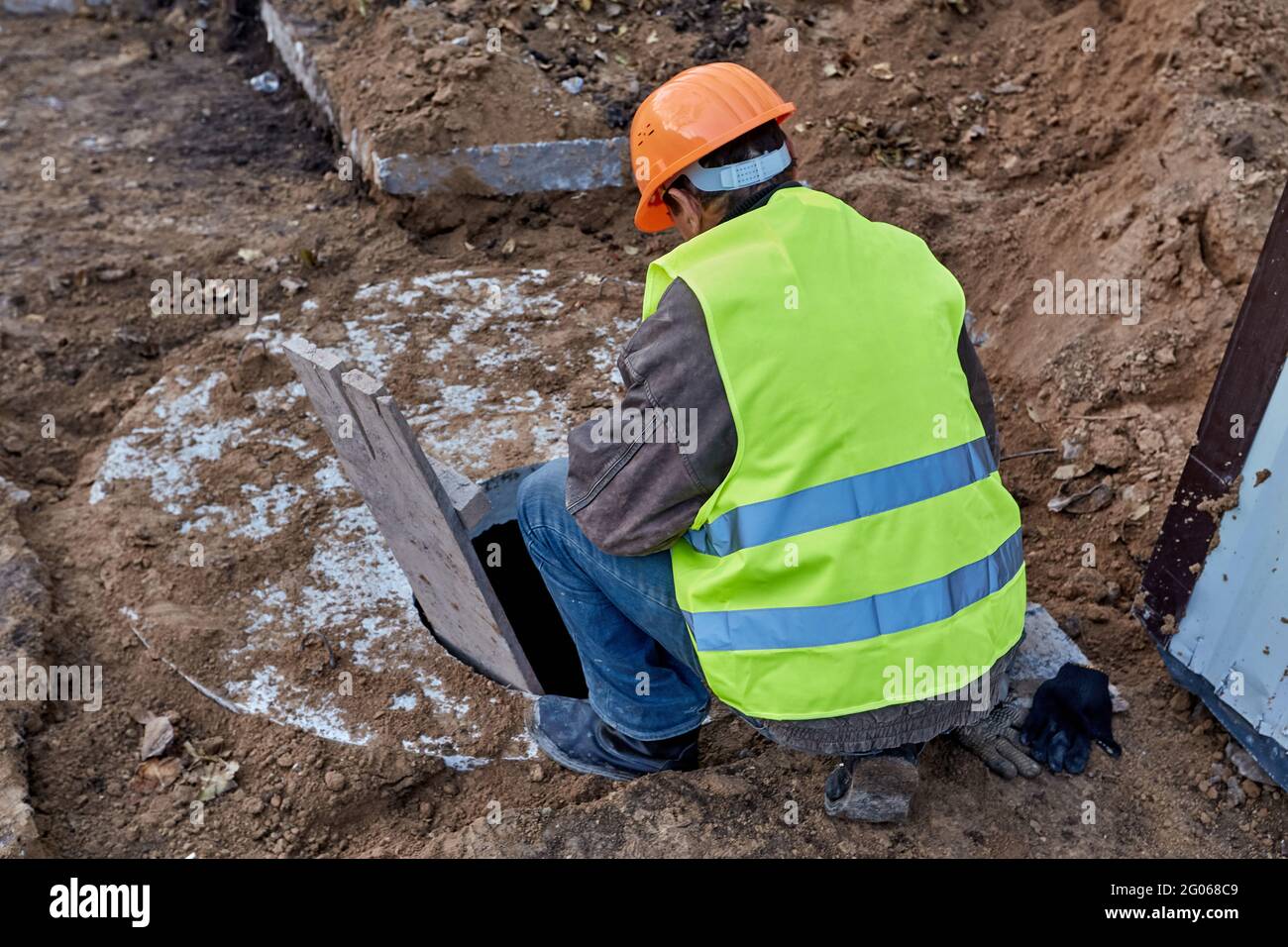 Worker is looking into a sewer hatch to check out communications ...