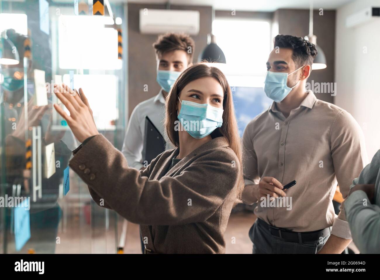 Colleagues having meeting using sticky notes on glass wall Stock Photo